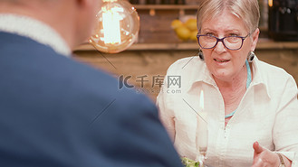 六十多岁的女人在餐厅吃饭时给丈夫讲了一个有趣的故事。