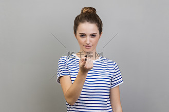 女人用手指呼唤你,用俏皮的表情看着相机,邀请约会.