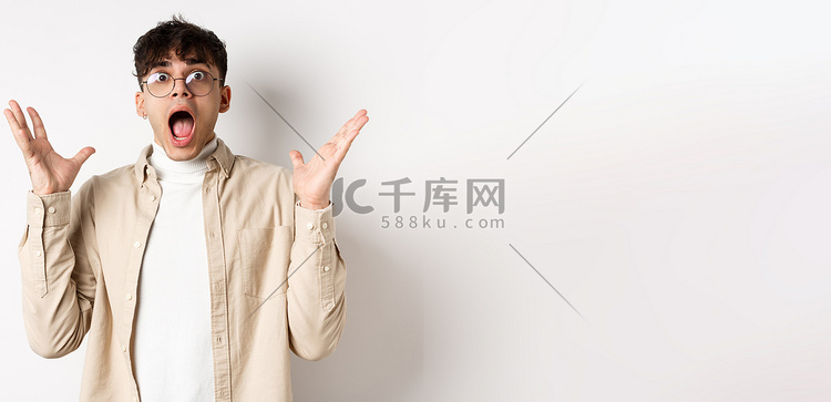 惊慌失措的年轻人惊慌失措,尖叫着,看上去焦躁不安,惊恐地跳起来,紧张地握手,站在白色背景上高清摄影大图-千库网