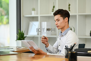 坐在现代工作场所的男性经理在笔记本上分析每周计划的侧视图