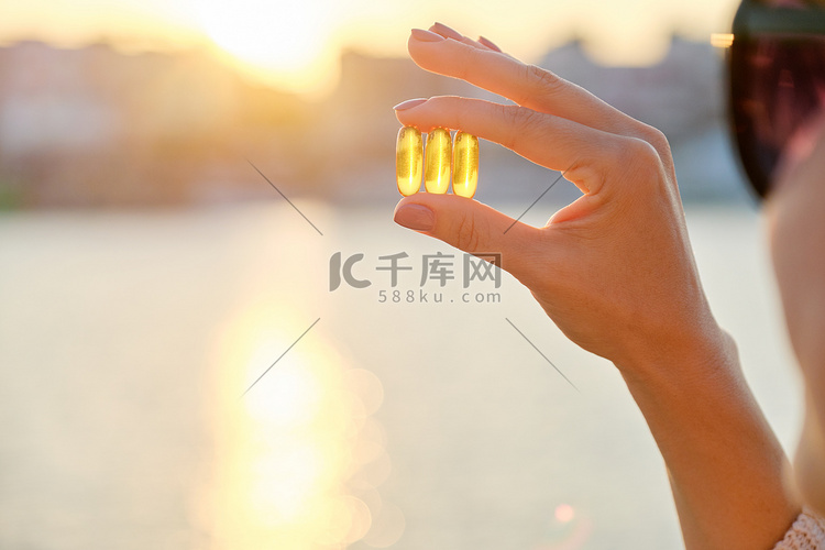 黄色凝胶胶囊维生素 d omega 3 在女性手中，太阳海背景高清摄影大图 千库网