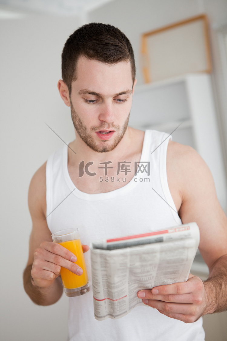一个年轻人边喝橙汁边看新闻的画像高清摄影大图-千库网