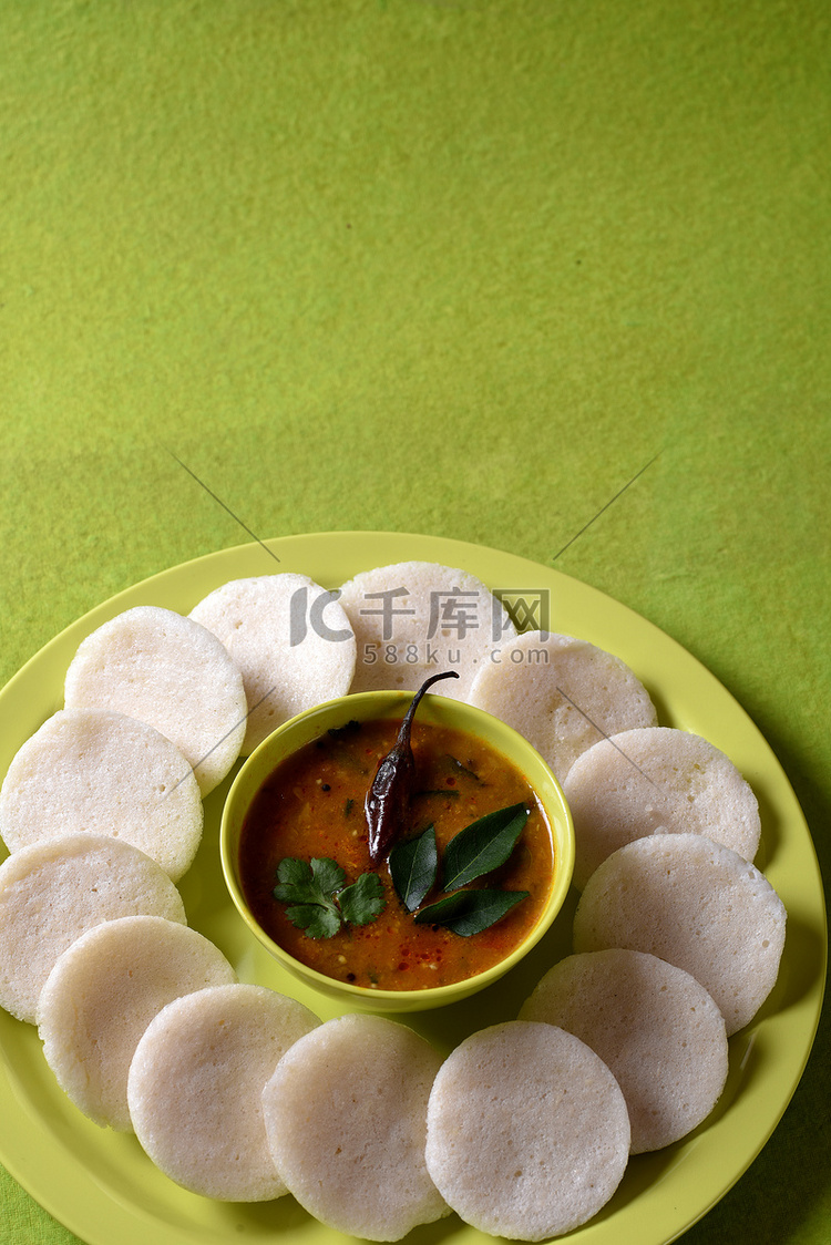 Idli 与 Sambar 在碗中的绿色背景，印度菜：南印度最喜欢的食物 rava idli 或 semolina idly 或 rava ...