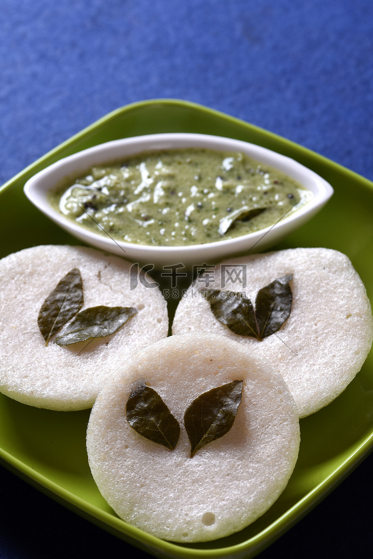 Idli 与椰子酸辣酱在蓝色背景，印度菜：南印度最喜欢的食物 rava idli 或 semolina idly 或 rava idly，配 ...