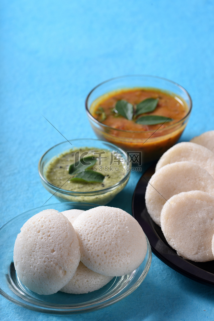 Idli 与 Sambar 和椰子酸辣酱在蓝色背景，印度菜：南印度最喜欢的食物 rava idli 或 semolina idly 或 ...