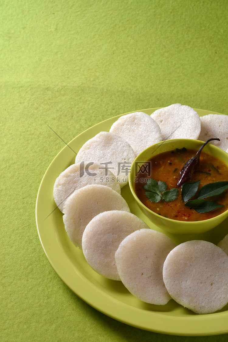 Idli 与 Sambar 在碗中的绿色背景，印度菜：南印度最喜欢的食物 rava idli 或 semolina idly 或 rava ...