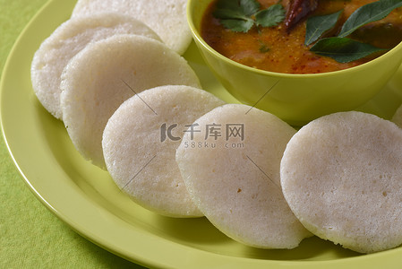 Idli 与 Sambar 在碗中的绿色背景，印度菜：南印度最喜欢的食物 rava idli 或 semolina idly 或 rava ...