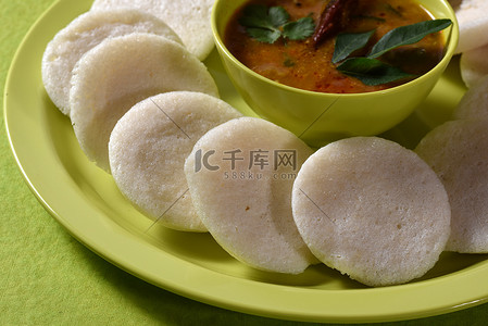 Idli 与 Sambar 在碗中的绿色背景，印度菜：南印度最喜欢的食物 rava idli 或 semolina idly 或 rava ...