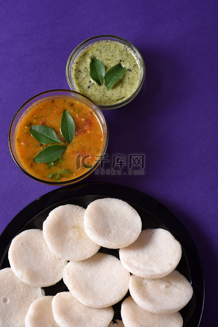 Idli 与 Sambar 和椰子酸辣酱在紫罗兰背景，印度菜：南印度最喜欢的食物 rava idli 或 semolina idly 或 ...