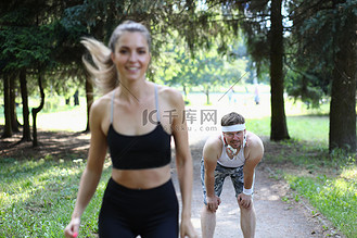 美丽的运动员女人和疲惫的男人在公园慢跑
