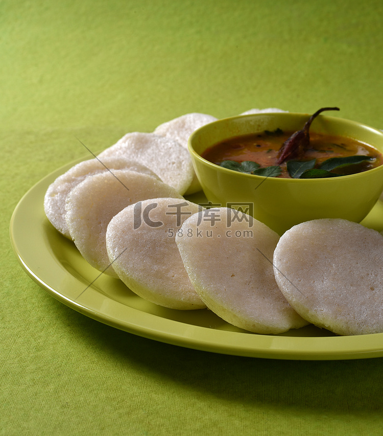 Idli 与 Sambar 在碗中的绿色背景，印度菜：南印度最喜欢的食物 rava idli 或 semolina idly 或 rava ...