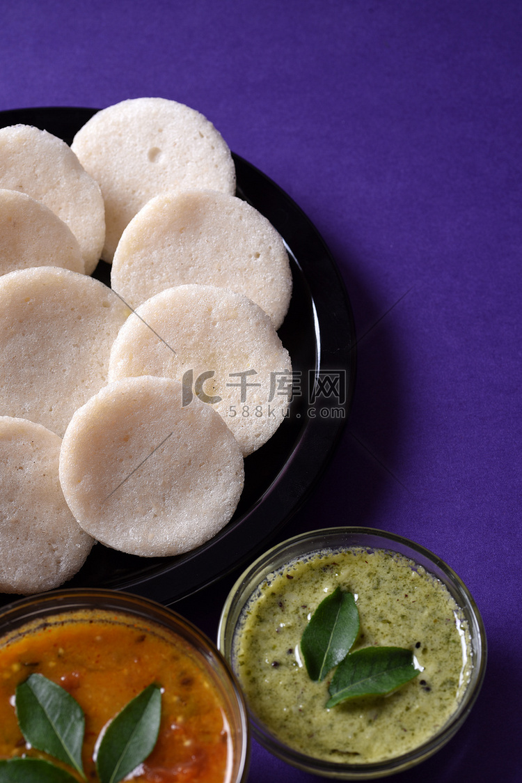 Idli 与 Sambar 和椰子酸辣酱在紫罗兰背景，印度菜：南印度最喜欢的食物 rava idli 或 semolina idly 或 ...