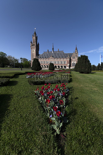 海牙，2019 年 4 月 24 日 — 国际法院所在地和平宫的日出，从宁静的花园欣赏建筑周围的郁金香花