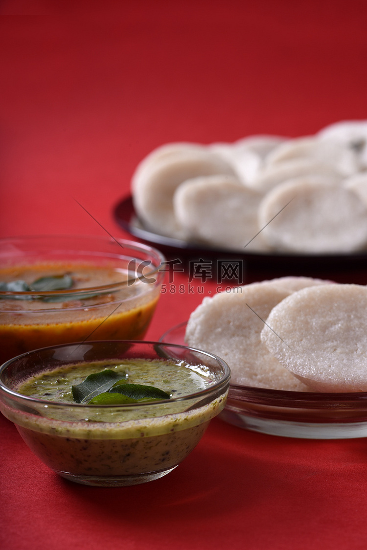 Idli 与 Sambar 和椰子酸辣酱在红色背景上，印度菜：南印度最喜欢的食物 rava idli 或 semolina idly 或 ...