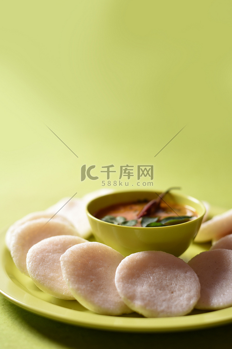 Idli 与 Sambar 在碗中的绿色背景，印度菜：南印度最喜欢的食物 rava idli 或 semolina idly 或 rava ...
