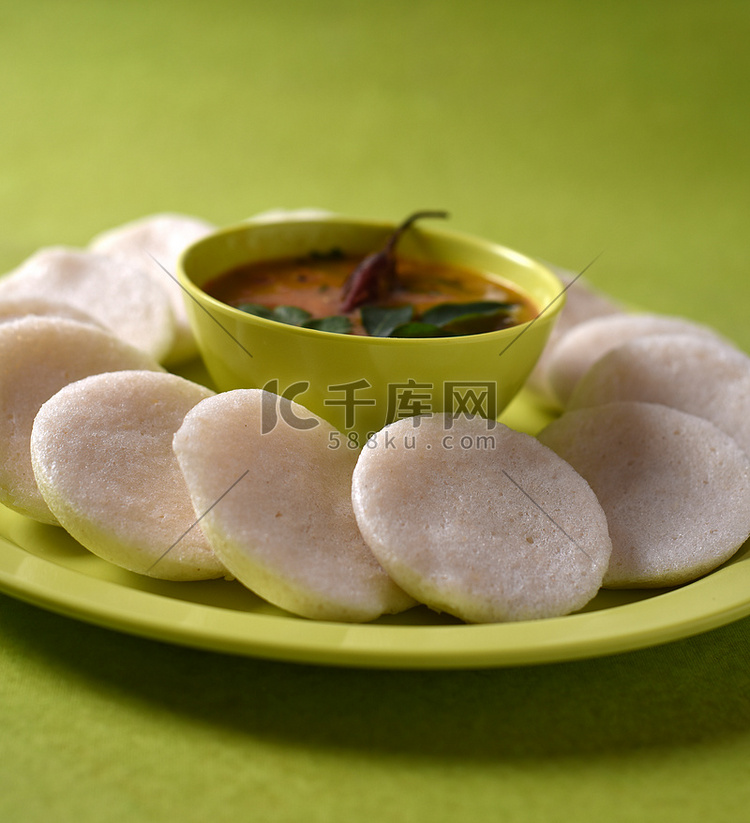 Idli 与 Sambar 在碗中的绿色背景，印度菜：南印度最喜欢的食物 rava idli 或 semolina idly 或 rava ...