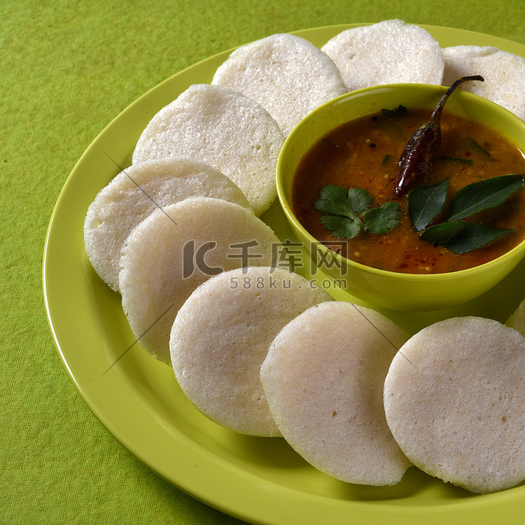 Idli 与 Sambar 在碗中的绿色背景，印度菜：南印度最喜欢的食物 rava idli 或 semolina idly 或 rava ...