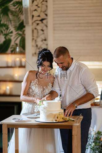 新婚夫妇愉快地切开并品尝结婚蛋糕