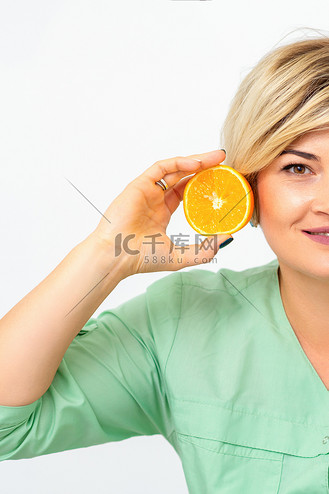 年轻微笑的金发女美容师的画像,白色背景上有一半的橙子.