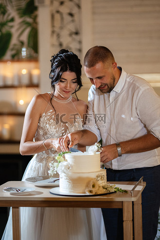 新婚夫妇愉快地切开并品尝结婚蛋糕
