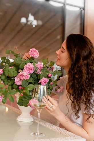 做梦的女人在夏季露台的咖啡馆里喝着含酒精的白葡萄酒,桌上放着一束
