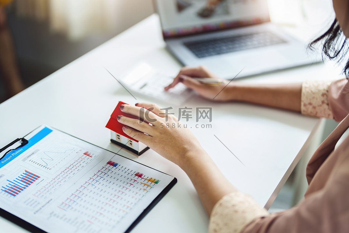 企业家、企业主、会计师、房地产经纪人，专注于桌面房屋模型，女性使用房屋净值预算计算器来评估她们的财务风险。高清摄影大图-千库网