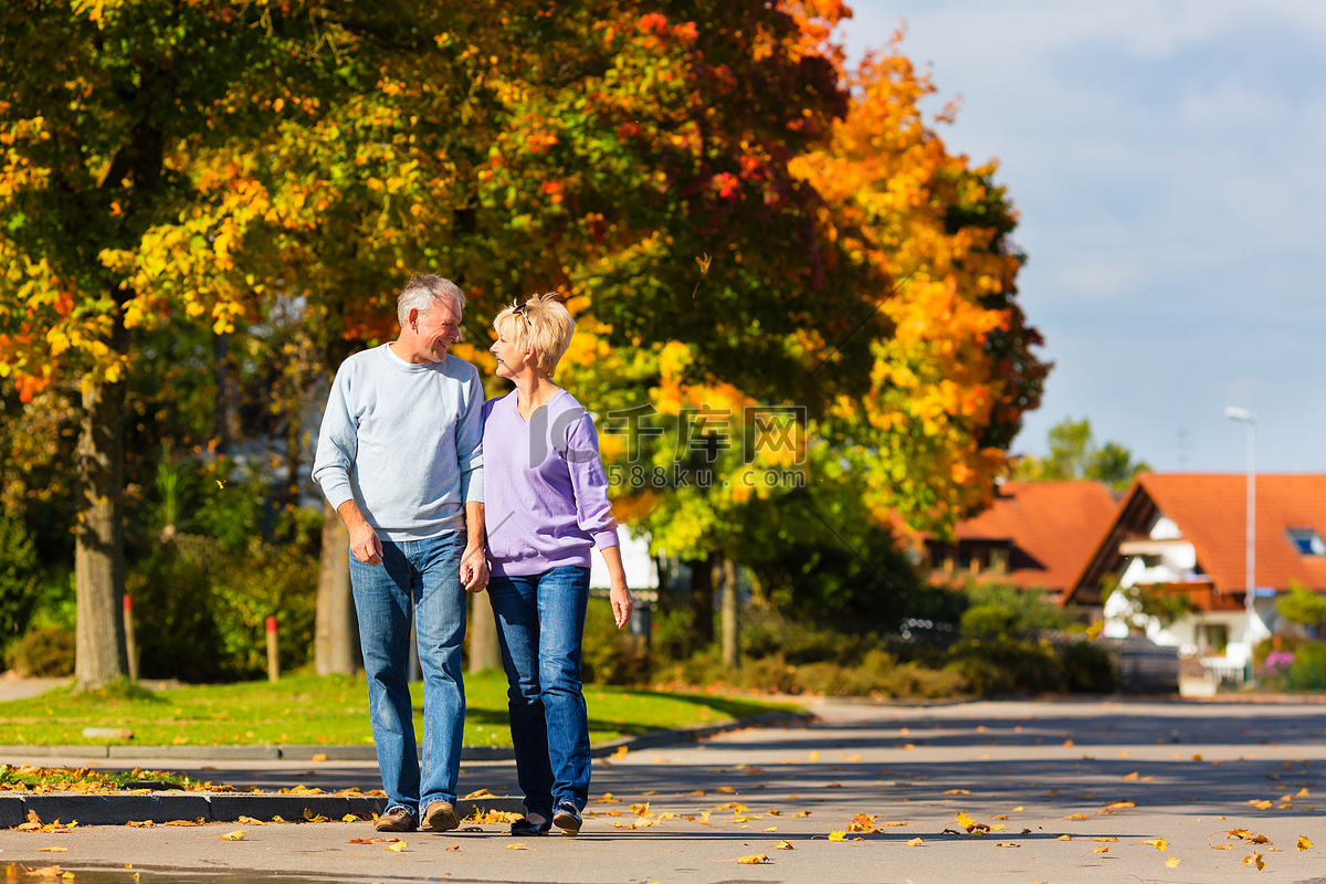 一对老年夫妇在秋天的公园里牵着手散步照片摄影图片_ID:143762402-Veer图库