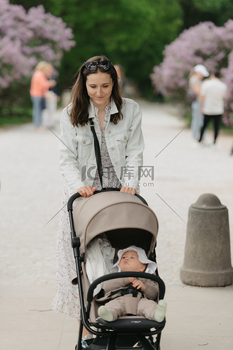 一位母亲推着婴儿车在公园散步.