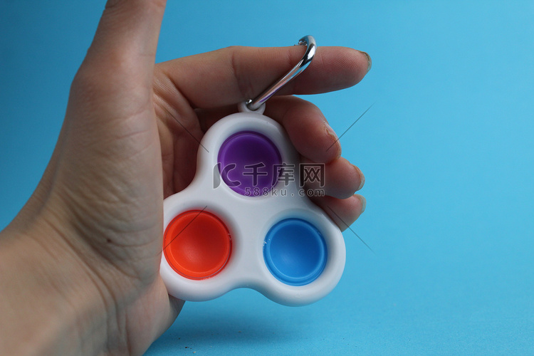 蓝色背景中手拿玩具抗压力 popit 简单酒窝高清摄影大图-千库网