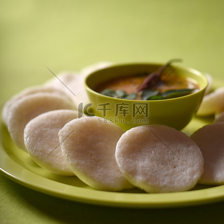 Idli 与水鹿在绿色背景的碗里，印度菜：南印度最喜欢的食物 rava idli 或粗面粉闲置或 rava 闲置，配上水鹿和绿色椰子酸辣酱 ...