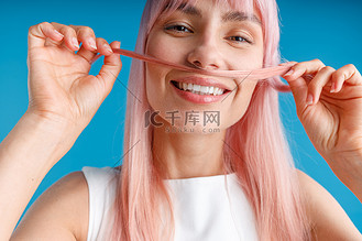 的年轻女子或十几岁的女孩在明亮的蓝色背景上留着一缕头发的小胡子
