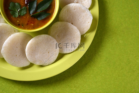 Idli 与水鹿在绿色背景的碗里，印度菜：南印度最喜欢的食物 rava idli 或粗面粉闲置或 rava 闲置，配上水鹿和绿色椰子酸辣酱 ...