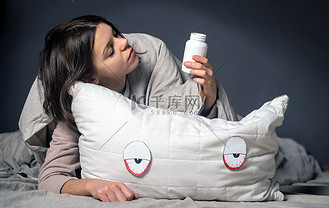 可爱悲伤的小女孩抱着一个白色的枕头,上面画着眼睛和脸.