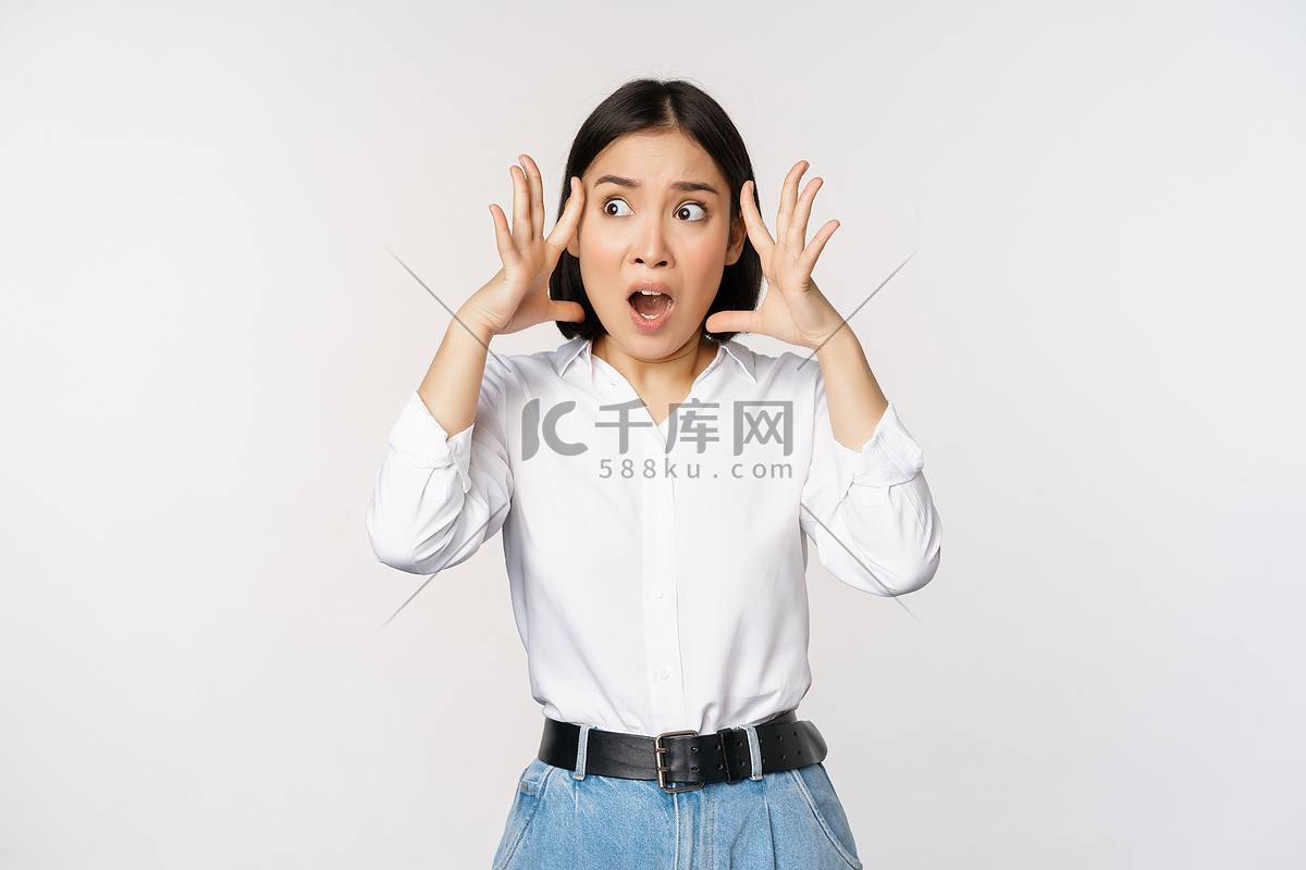 一幅震惊焦虑的亚洲女性惊慌失措、双手抱头、忧心忡忡、在白色背景下站着沮丧和害怕的画面高清摄影大图-千库网