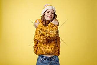 乐观迷人,开朗的年轻女子感到幸运,快乐地拥抱自己,就像新的温暖舒适