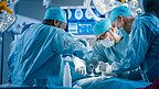 在医院手术室对病人进行侵入性手术的专业外科医生多样化小组。外科医生使用仪器.