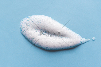淋浴露图片素材_面部清洁慕斯样品.蓝色背景上的白色清洁剂泡沫泡沫.