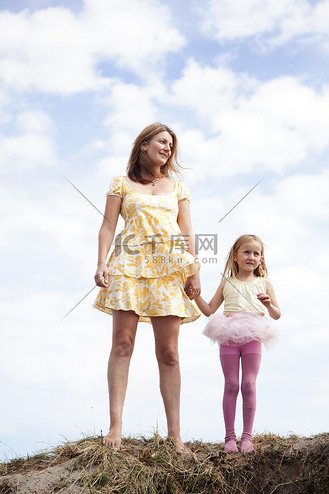 母亲和女儿在英国威尔士的沙丘上手牵手