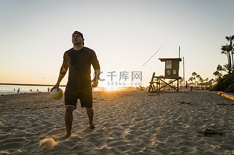 美国加利福尼亚州纽波特海滩一名年轻男子在日落时打沙滩排球