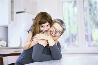 祖母的厨房图片素材_女孩在厨房餐桌上拥抱祖母的肖像