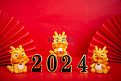 2024新年三个卡通龙红色背景摆放摄影图配图