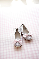 白色上堆放着两双灰色方格粉色蝴蝶结芭蕾舞拖鞋