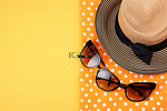 橙色和黄色背景上的沙滩帽太阳镜和凉鞋