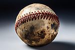 一个生锈的球，呈现深棕色色调，棒球中间有一条红线