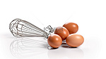 3d 渲染的白色背景上的棕色鸡蛋旁边的钢丝搅拌器和打蛋器