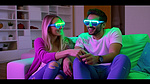 戴着 3D 眼镜的夫妇在家里的地板上看电视时突然大笑起来