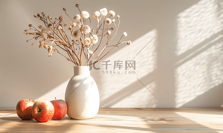 白色花瓶里的干白花和木桌上的苹果