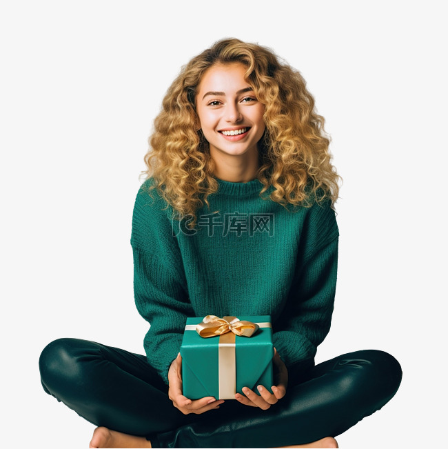 穿着毛衣的女孩坐在圣诞树旁，拿