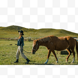 在草原上牵着马的美女