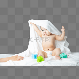 披着被子玩耍的男婴床上玩玩具